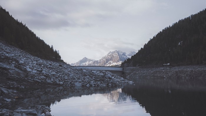 Snowy mountains behind a dam and lake