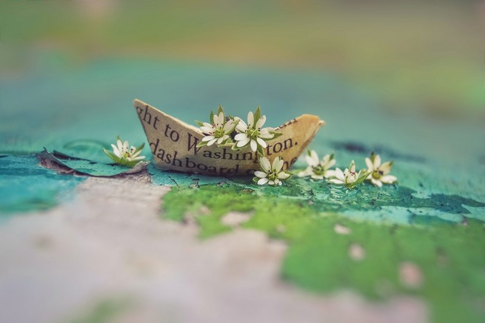 Paper boat with flowers on a textured surface