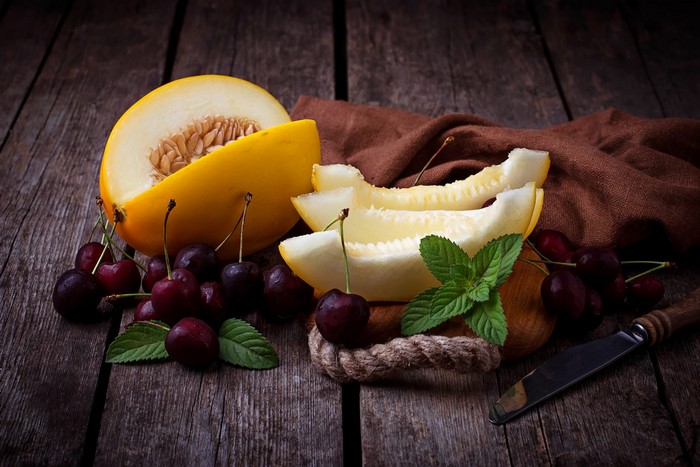 Melon, Cherries, Mint, and Knife on Wooden Surface