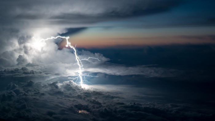 Lightning strike over clouds at dusk