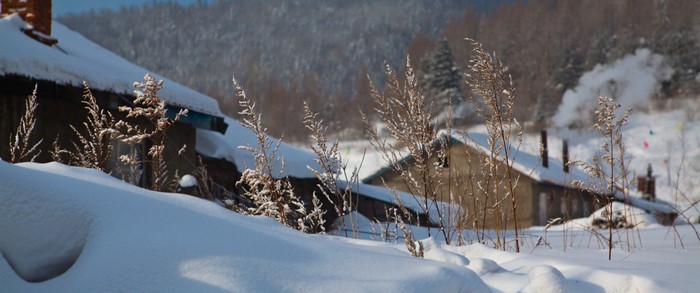 Snowy village with smoke rising from chimneys