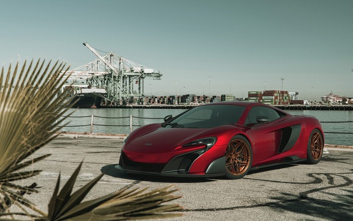 Red McLaren 675LT parked at a port with cranes