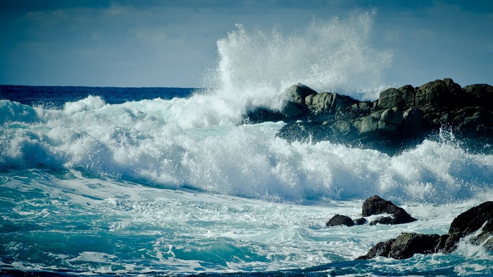 Waves crashing against rocks on a sunny day