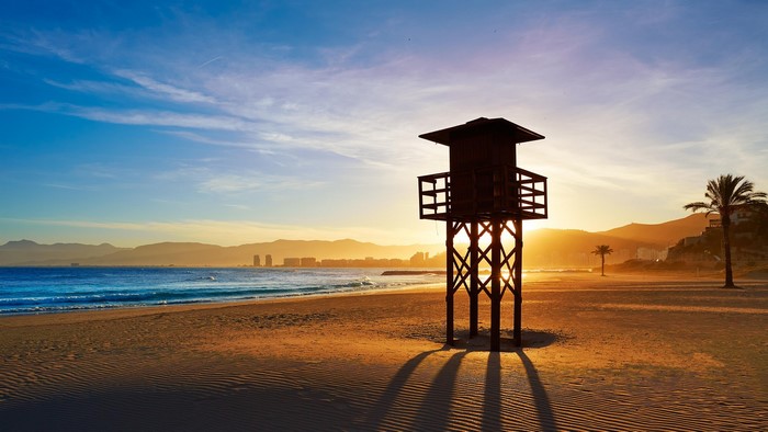 Lifeguard tower on a beach at sunset with mountains