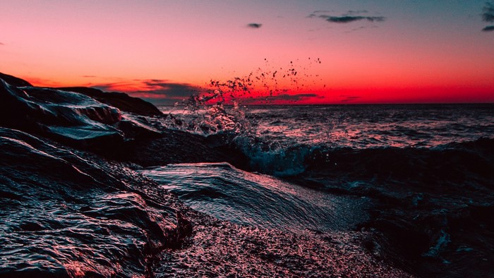 Waves crashing on rocks at sunset