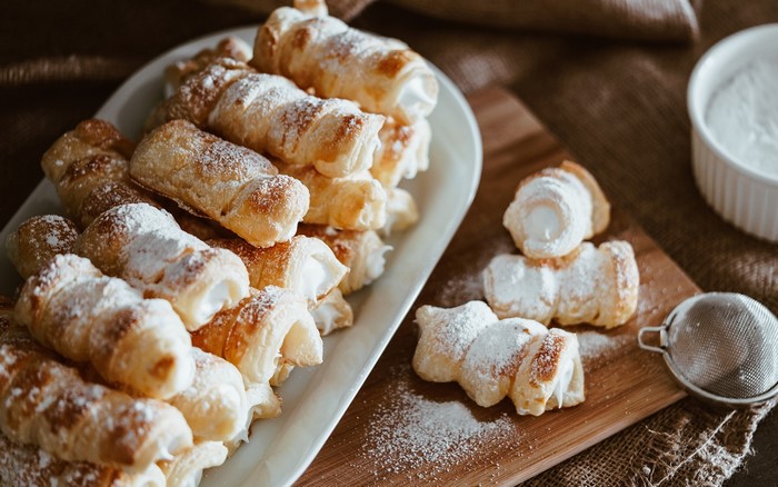 Cream-filled pastries dusted with powdered sugar on a platter