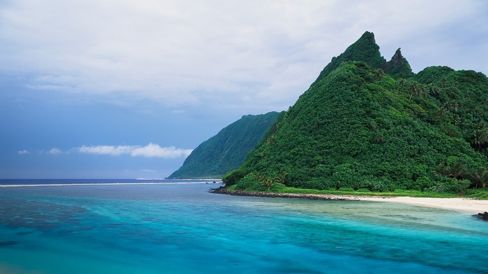 Green mountains meet turquoise sea and white sand beach