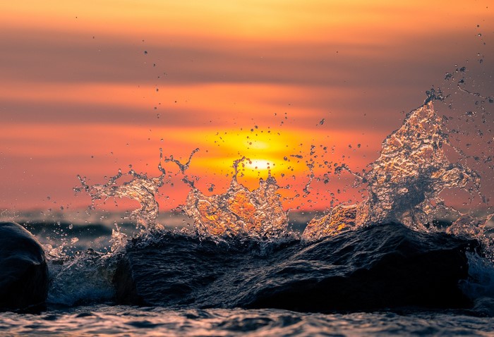 Waves crashing on rocks at sunset