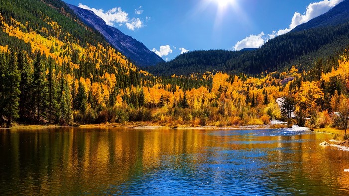 Autumn mountain lake with sun and clouds