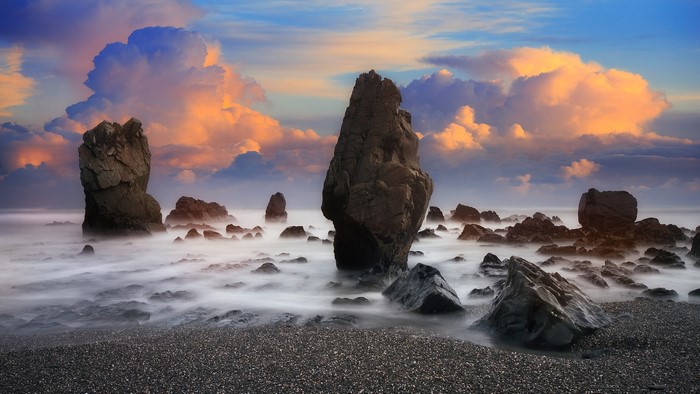 Long exposure of rocks on a beach with dramatic clouds