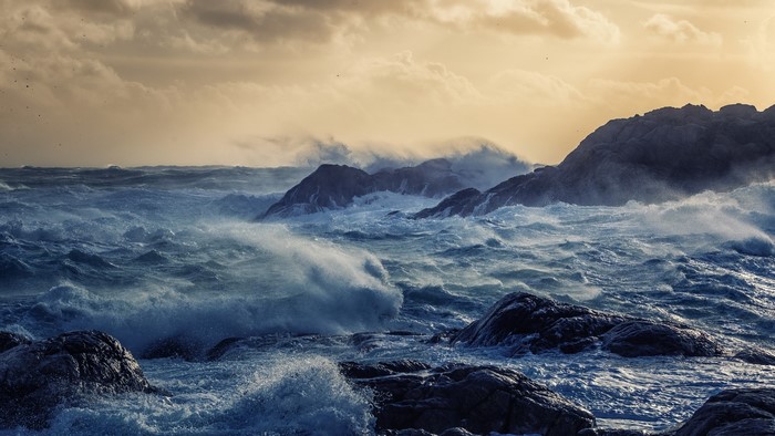 Stormy sea crashing against rocky coast under cloudy sky