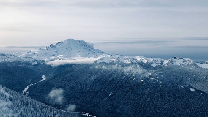 Snow-covered mountains and forest valley aerial view