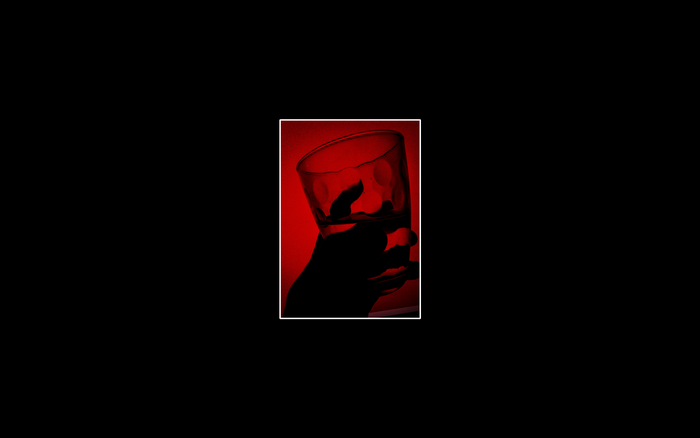 Silhouette of a hand holding a glass with red background