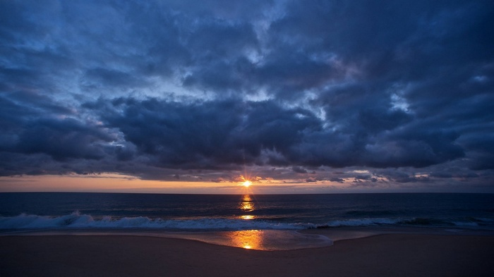 Sunset over the ocean with dark clouds