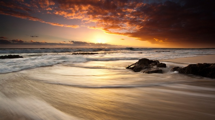 Sunset over the ocean with waves and rocks