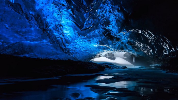 Blue ice cave with water and rock formations