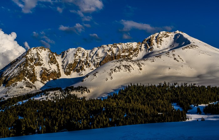 Snowy mountains under a blue sky with clouds