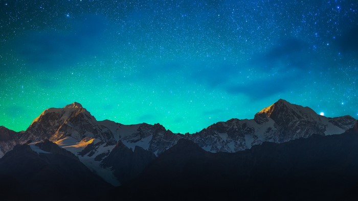 Snowy mountains under a starry night sky with aurora