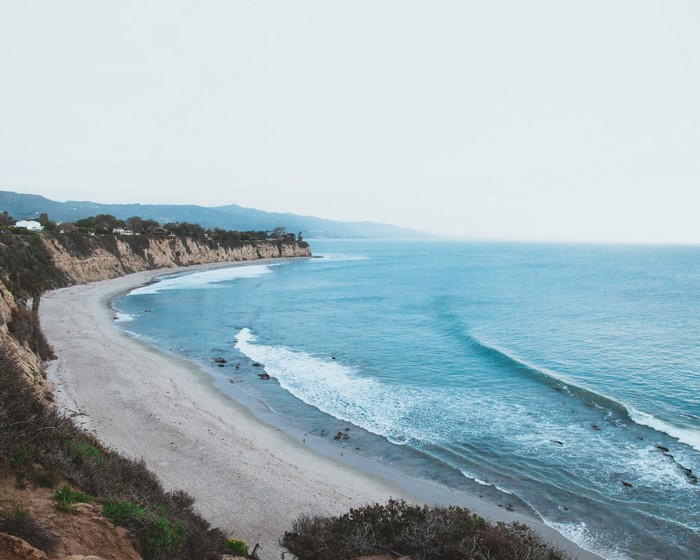 Coastal cliffs overlooking a sandy beach and blue ocean