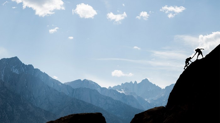 Two people climbing a steep mountain face