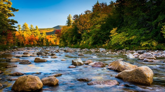 River flowing through rocky terrain with autumn foliage in New Hampshire