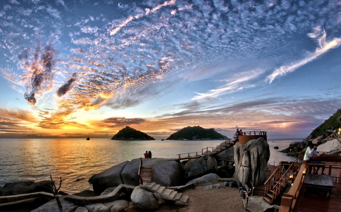 Sunset over islands with a wooden walkway and people