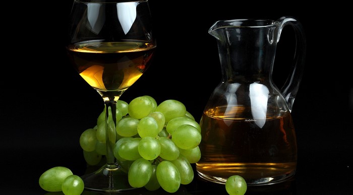 White wine in a glass and carafe with green grapes