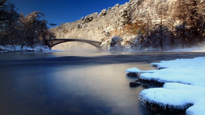 Winter bridge over a misty river in Scotland