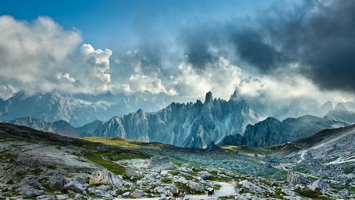 Dolomites mountains landscape with a house and clouds