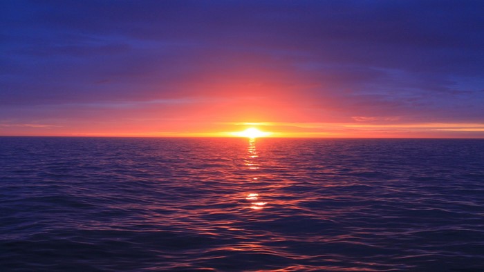 Sunset over the ocean with purple clouds