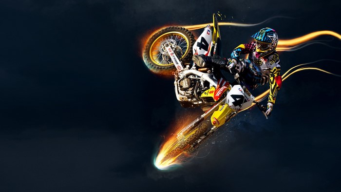 Motocross rider performing a stunt with fiery trails