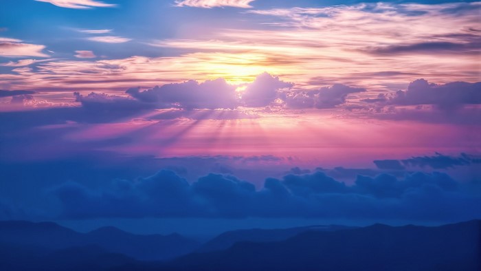 Sunset sky with sun rays over mountains