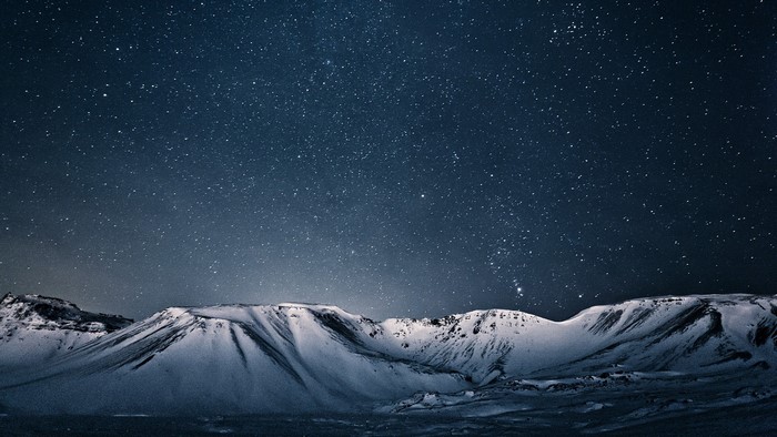 Snowy mountains under a starry night sky in Iceland