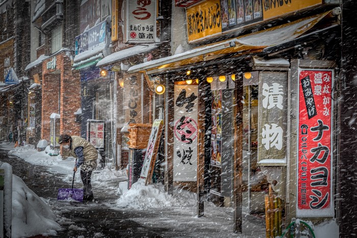 Person shoveling snow in a Japanese city during winter