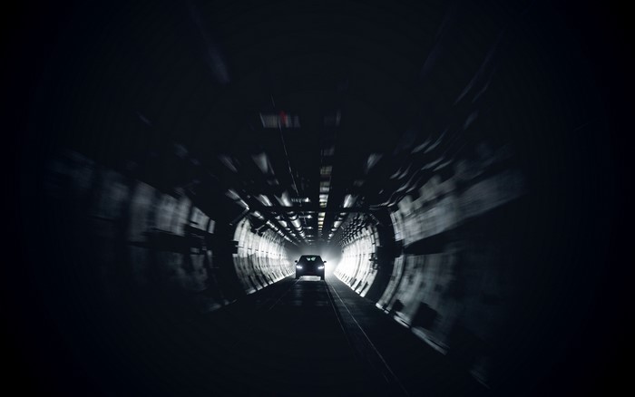 Car driving through a dark tunnel