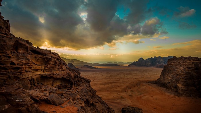 Sunset over Wadi Rum desert landscape with rocky mountains and clouds