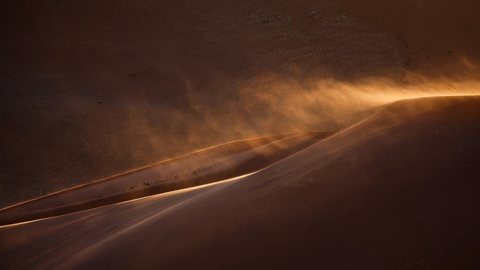 Sand dunes in Namibia at sunset with wind blowing