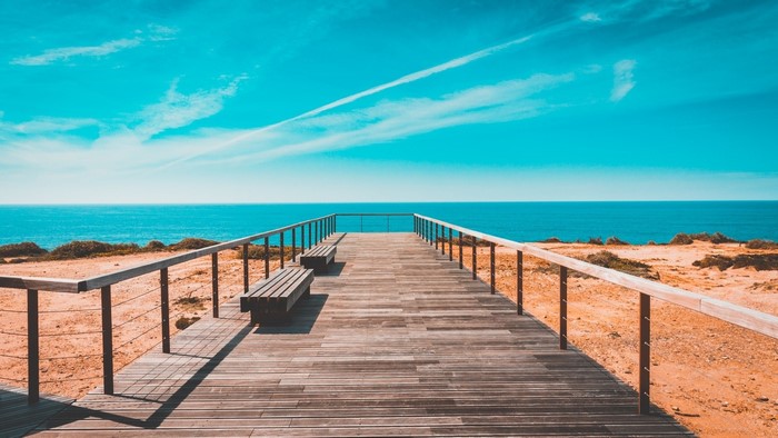 Wooden boardwalk leading to the ocean with benches