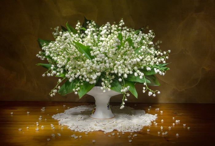 Lily of the valley flowers in a vase on a wooden surface