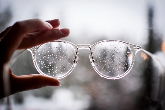 Hand holding glasses with water drops