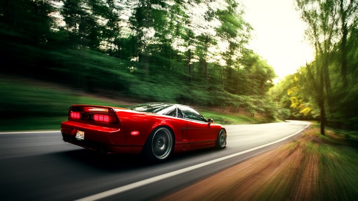 Red Honda NSX driving on a forest road