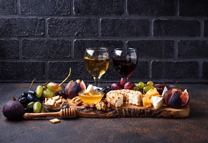 Wine, cheese, fruit, and nuts on a cutting board
