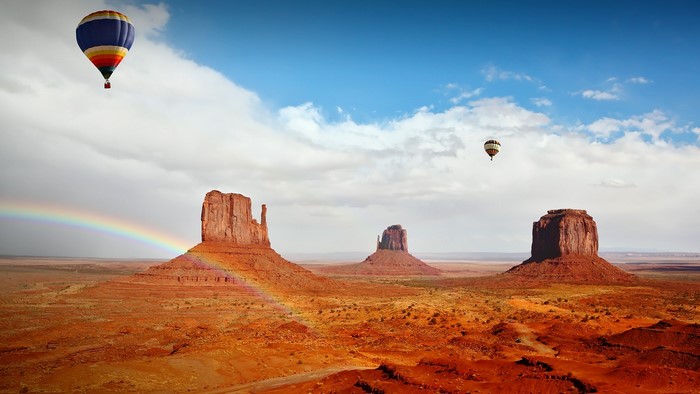 Hot air balloons over Monument Valley with rainbow