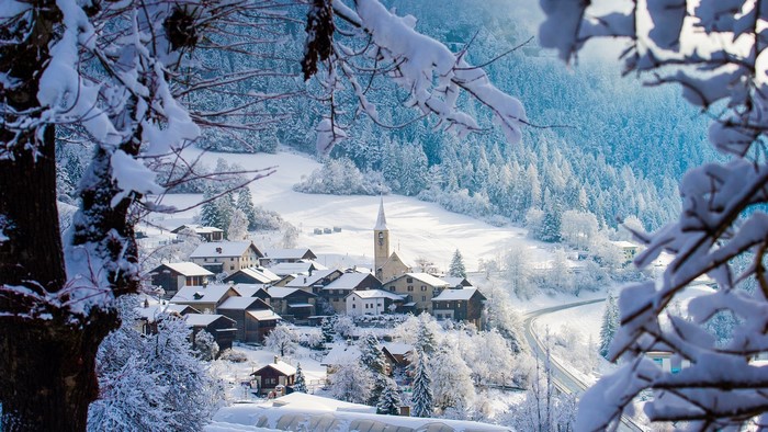 Snowy village with church in a winter mountain landscape