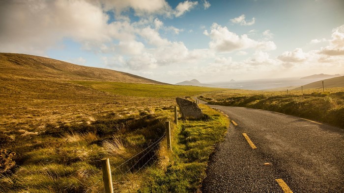 Road through Irish landscape with hills and ocean