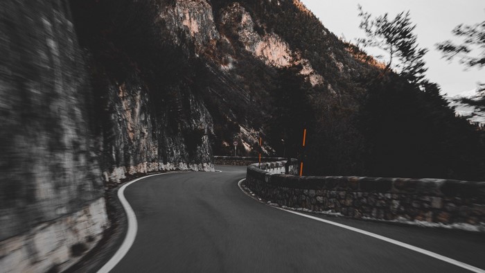 Curved mountain road with stone wall
