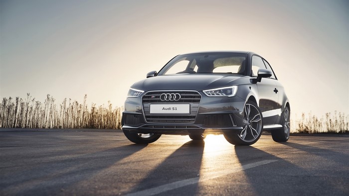 Audi S1 parked on asphalt with dry plants and sunset