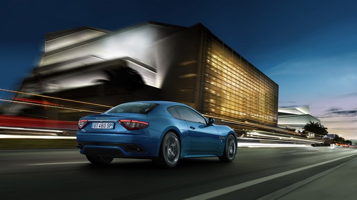 Blue Maserati GranTurismo driving on a road at night