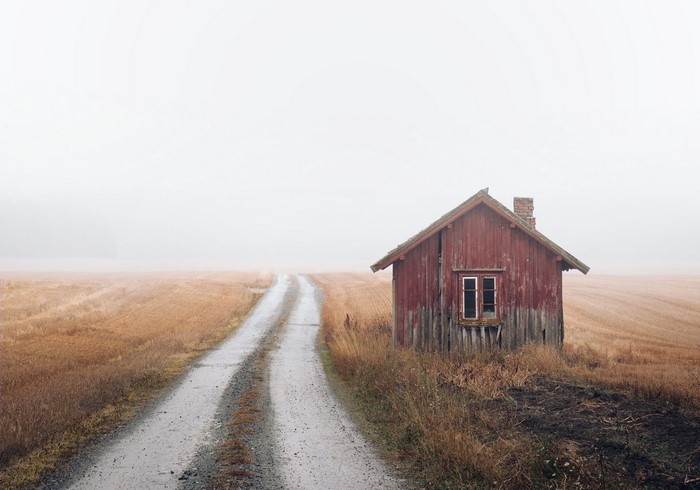 Red house on a dirt road in mist