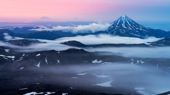 Volcanoes shrouded in mist at sunrise in Kamchatka, Russia